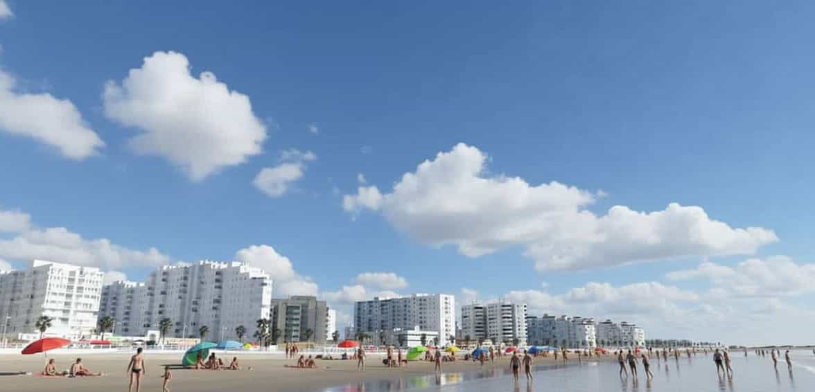 Golden sands of Valdelagrana Beach with sunbathers and umbrellas
